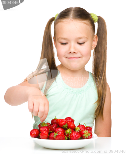 Image of Happy little girl is eating strawberries