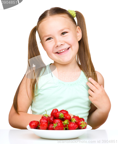 Image of Cheerful little girl is eating strawberries