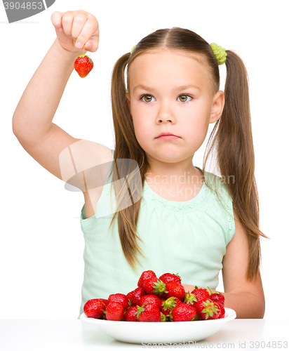 Image of Little girl is eating strawberries