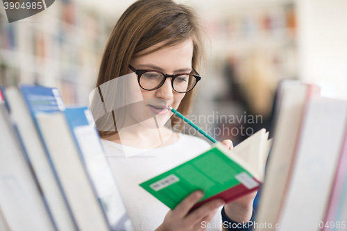 Image of portrait of famale student selecting book to read in library