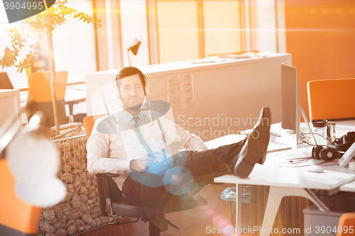 Image of relaxed young businessman first at workplace at early morning