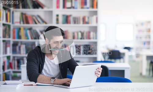 Image of student in school library using laptop for research