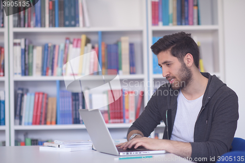 Image of student in school library using laptop for research