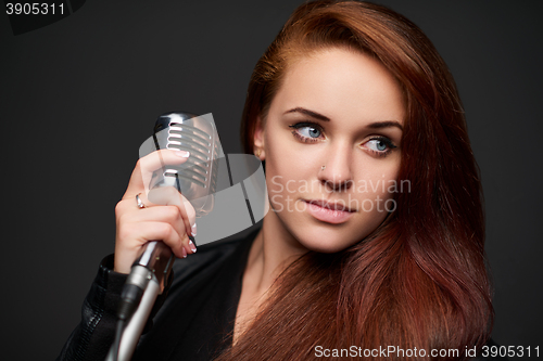 Image of Closeup of young woman with retro microphone