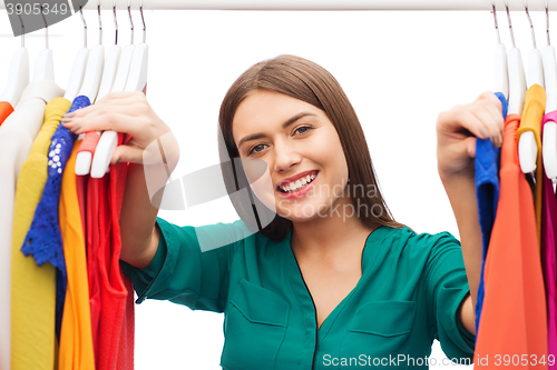 Image of happy woman choosing clothes at home wardrobe