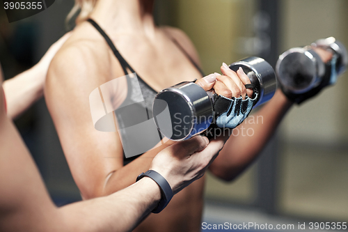 Image of woman with dumbbells flexing muscles in gym