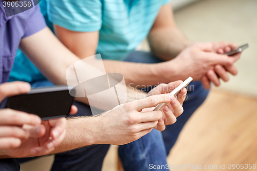 Image of close up of male friends with smartphones at home