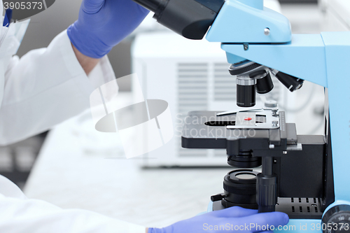 Image of close up of hands with microscope and blood sample