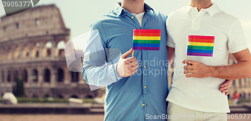 Image of close up of male gay couple with rainbow flags