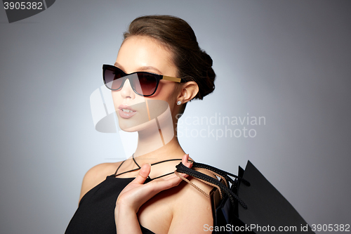 Image of happy woman in black sunglasses with shopping bags