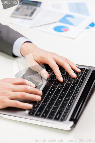 Image of close up of businessman hands typing on laptop