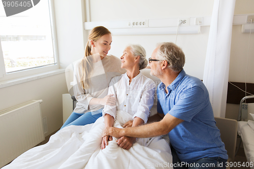 Image of happy family visiting senior woman at hospital