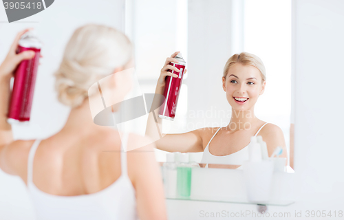 Image of woman with hairspray styling her hair at bathroom