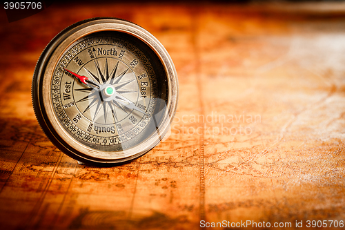 Image of Vintage compass lies on an ancient world map.