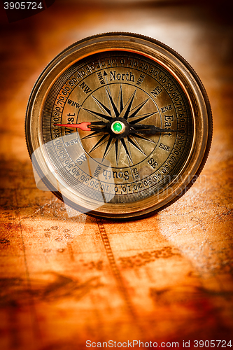 Image of Vintage compass lies on an ancient world map.