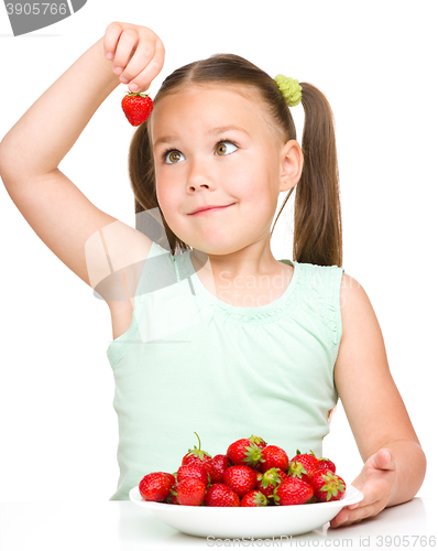 Image of Cheerful little girl is eating strawberries