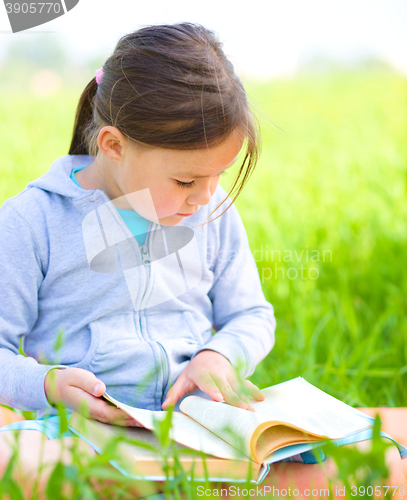 Image of Little girl is reading a book outdoors