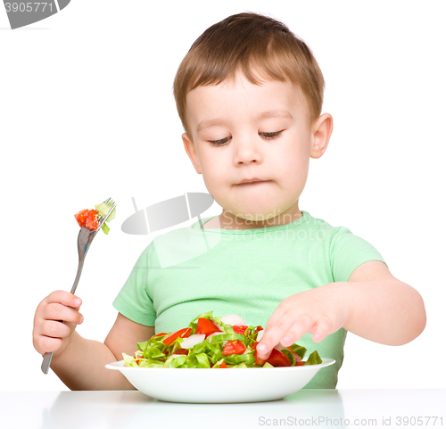 Image of Cute little boy is eating vegetable salad