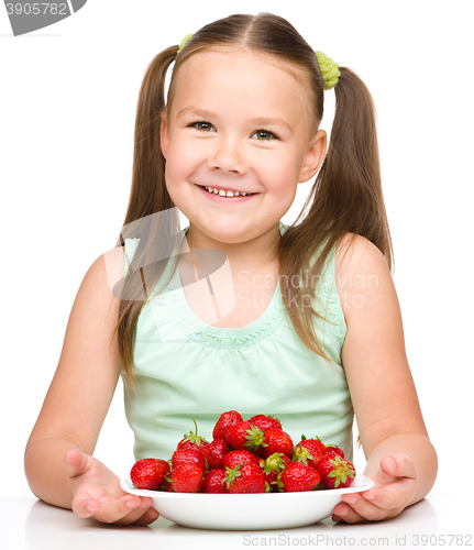 Image of Cheerful little girl is eating strawberries