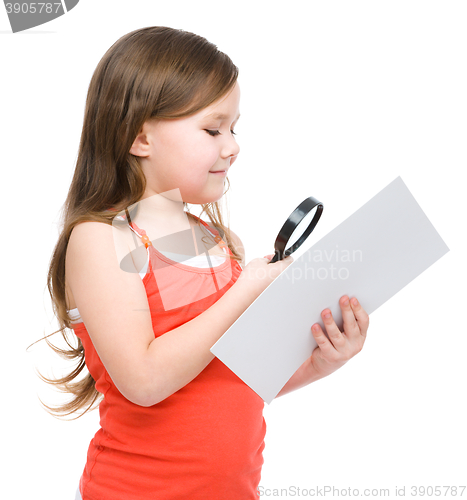 Image of Girl is looking at big paper using magnifier