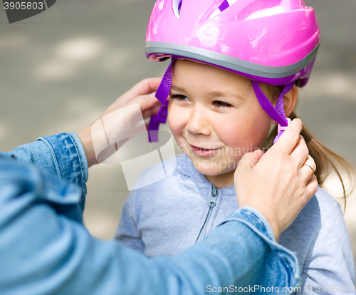 Image of Mother is helping her daughter with safety helmet