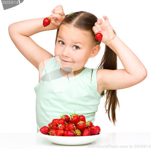 Image of Happy little girl is eating strawberries