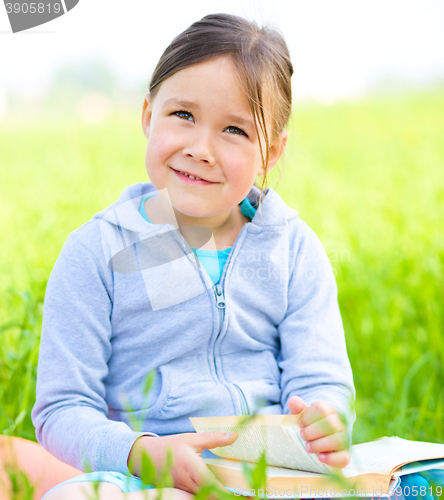 Image of Little girl is reading a book outdoors