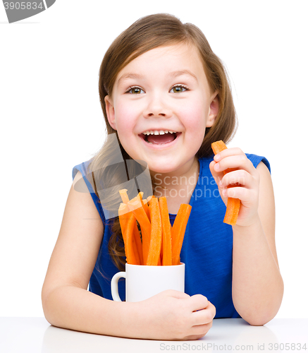 Image of Cute little girl is eating carrot