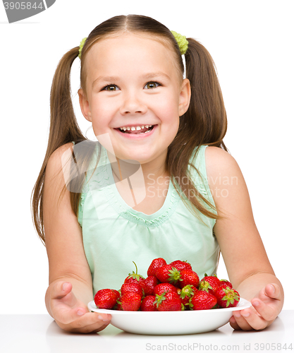 Image of Cheerful little girl is eating strawberries