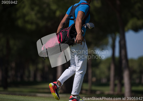 Image of golf player walking and carrying bag