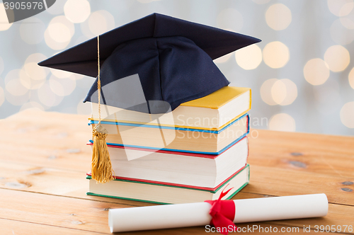 Image of close up of books with diploma and mortarboard