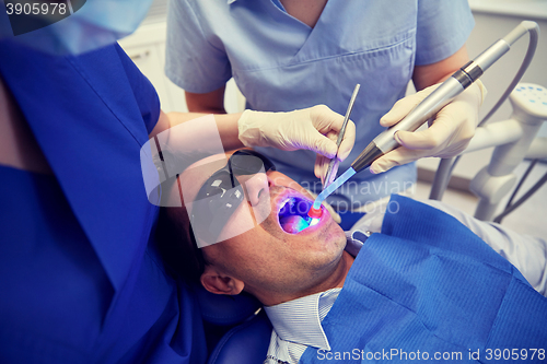 Image of dentists treating male patient teeth at clinic