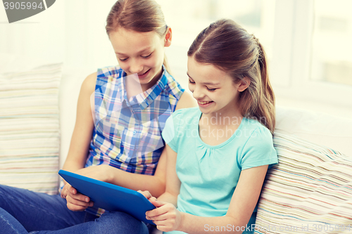 Image of happy girls with tablet pc sitting on sofa at home