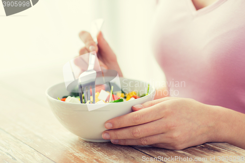 Image of close up of young woman eating salad at home