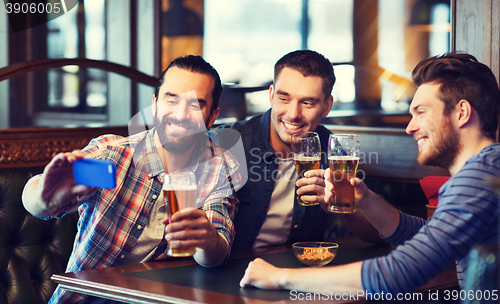 Image of friends taking selfie and drinking beer at bar