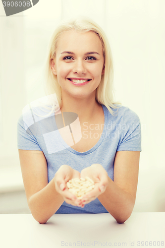 Image of happy woman holding pills or capsules at home