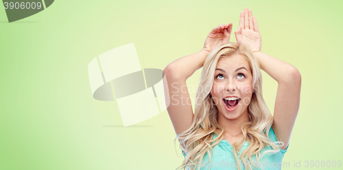 Image of happy smiling young woman making bunny ears