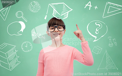 Image of happy little girl in eyeglasses pointing finger up