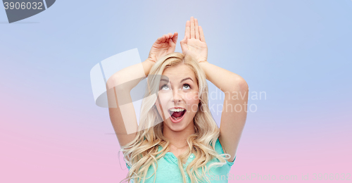 Image of happy smiling young woman making bunny ears