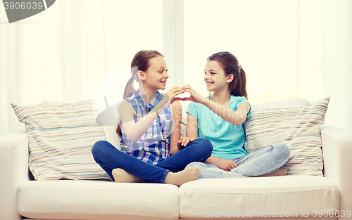 Image of happy little girls showing heart shape hand sign