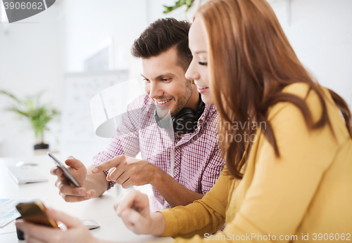 Image of happy creative team with smartphones at office