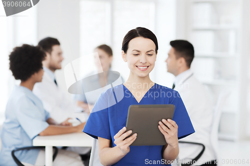 Image of happy doctor with tablet pc over team at clinic