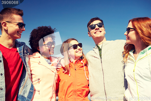 Image of happy teenage friends in shades talking on street