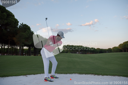 Image of golfer hitting a sand bunker shot on sunset