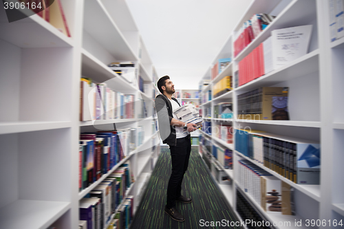 Image of Student holding lot of books in school library