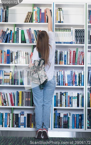 Image of famale student selecting book to read in library