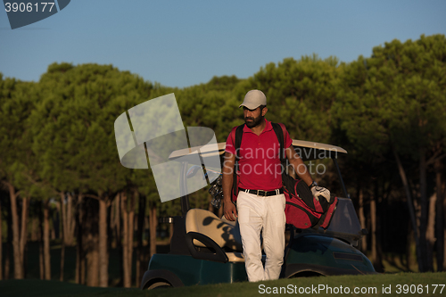 Image of golfer  walking and carrying golf  bag