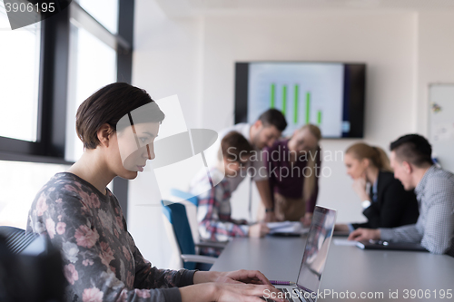 Image of young business woman at office working on laptop with team on me