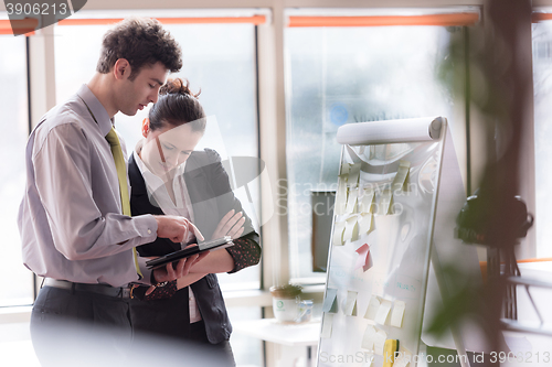 Image of young couple working on flip board at office
