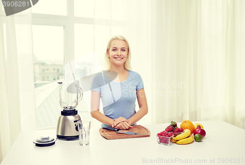 Image of smiling woman with blender and fruits at home